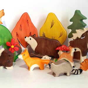 May include: A set of wooden animal figurines, including a wolf, fox, bear, deer, raccoon, hedgehog, and squirrel, along with trees and mushrooms. The figurines are painted in realistic colors and have detailed features.