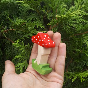 May include: A wooden toy mushroom with a red cap with white polka dots and a green base.