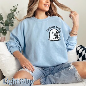 Pu&ograve; includere: Felpa blu chiaro con un fantasma che tiene una tazza di caff&egrave; e la scritta "Literally Dead" sul davanti.