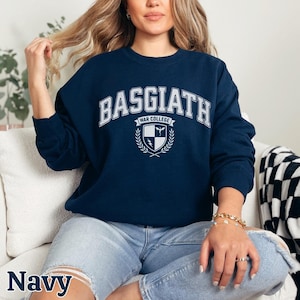Peut inclure: Sweat-shirt bleu marine avec l'inscription blanche "BASGIATH WAR COLLEGE". En dessous, un &eacute;cusson avec un bouclier, une &eacute;p&eacute;e et une couronne de laurier. Le mot "Navy" est &eacute;crit en bas de l'image.