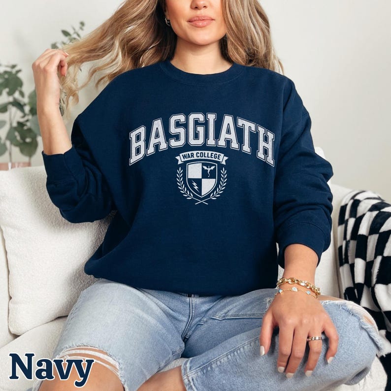 Peut inclure: Sweat-shirt bleu marine avec l'inscription blanche "BASGIATH WAR COLLEGE". En dessous, un &eacute;cusson avec un bouclier, une &eacute;p&eacute;e et une couronne de laurier. Le mot "Navy" est &eacute;crit en bas de l'image.