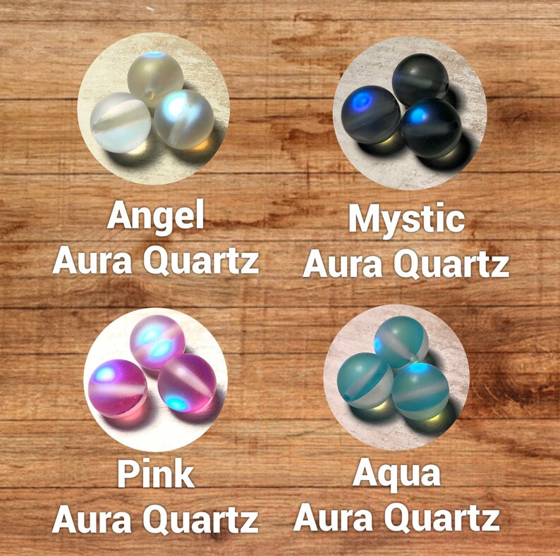 Puede incluir: Cuatro conjuntos de esferas de cuarzo Aura en los colores Angel, Mystic, Pink y Aqua. Cada conjunto contiene tres esferas, exhibidas sobre un fondo de madera. El texto "Angel Aura Quartz", "Mystic Aura Quartz", "Pink Aura Quartz" y "Aqua Aura Quartz" se muestra debajo de cada conjunto.