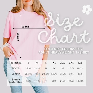 May include: A pink Comfort Colors 1717 adult heavyweight t-shirt with a size chart. The chart shows measurements in inches for width, length, and sleeve center back for sizes S through 4XL. The shirt is being modeled.