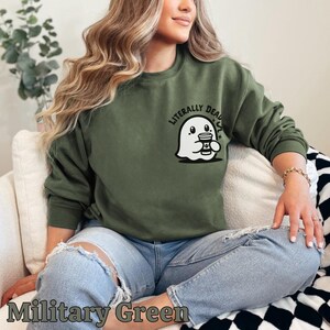 Pu&ograve; includere: Una felpa verde con un fantasma bianco che tiene una tazza di caff&egrave; e la scritta "Literally Dead" stampata sul davanti.