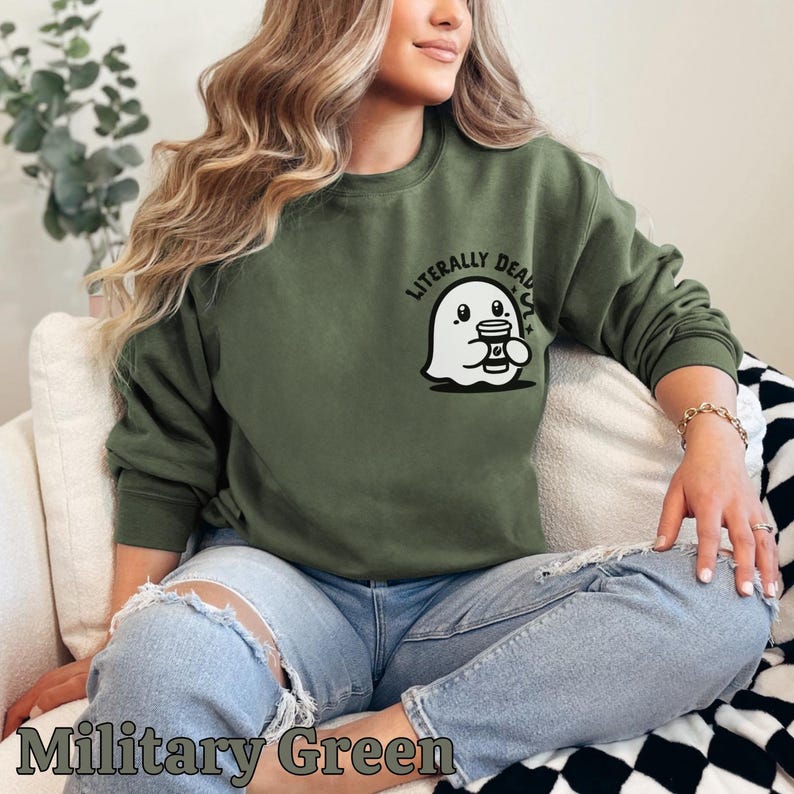 Pu&ograve; includere: Una felpa verde con un fantasma bianco che tiene una tazza di caff&egrave; e la scritta "Literally Dead" stampata sul davanti.
