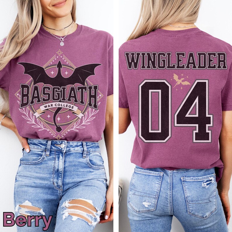 K&ouml;nnte beinhalten: Beerenfarbenes T-Shirt mit einem Aufdruck "BASGIATH WAR COLLEGE" und einer Drachenillustration. Auf der R&uuml;ckseite des Shirts steht "WINGLEADER 04". Das Shirt wird mit einer blauen Jeans kombiniert.