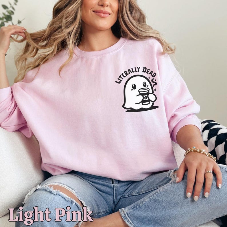 Pu&ograve; includere: Una felpa rosa chiaro con un fantasma che tiene una tazza di caff&egrave; e la scritta "LITERALLY DEAD" stampata sul davanti.