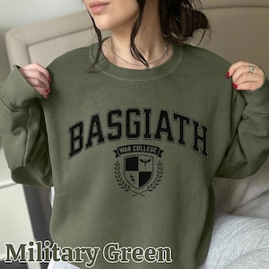 Peut inclure: Sweat-shirt vert militaire avec l'inscription "BASGIATH WAR COLLEGE" en lettres noires. Un &eacute;cusson est plac&eacute; sous le texte. Le sweat-shirt est de couleur vert militaire uni.