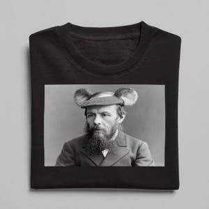 Könnte beinhalten: Schwarzes Sweatshirt mit Rundhalsausschnitt und einem Schwarz-Weiß-Bild eines Mannes, der einen Hut mit zwei flauschigen, ohrenartigen Aufsätzen trägt. Der Mann hat einen langen Bart und trägt eine Anzugjacke. Das Sweatshirt ist gefaltet.