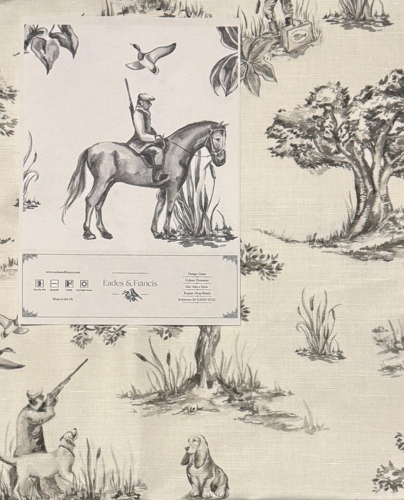 May include: Black and white fabric featuring a repeating pattern of a hunter on horseback, a hunter with a dog, and a hunter with a gun. The fabric also features trees, bushes, and reeds. The fabric is made by Eades & Francis and has the reference number EF GADO TC12.