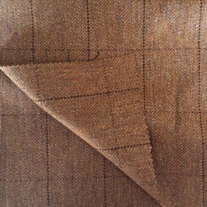 May include: Brown tweed fabric with a subtle checkered pattern. The fabric has a soft, textured feel.