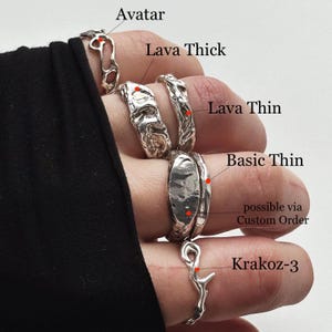 Close lifestyle photo of a left hand wearing a mixed solid 925 sterling silver look, with labels naming each ring. From pinky to thumb: openwork Avatar; chunky, heavy freeform Lava Thick with uneven wide lava relief; unique wavy Lava Thin with irregular texture; smooth slim Basic Thin beside a wider custom-order band; and openwork Krakoz-3. The Lava Thick and Thin designs add fluid abstract contrast to the stacked silver set.