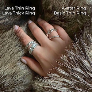 Close-up of a hand adorned with four handcrafted silver rings — Lava Thin Ring, Lava Thick Ring, Avatar Ring, and Basic Thin Ring — resting on natural wolf fur. Each ring features a unique texture, from organic molten patterns to minimalist curves. Text labels on the image identify the names of each ring, styled together in a bold stacked look.