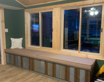 Puede incluir: Un asiento de ventana incorporado con un cojín beige y un frente de panel de madera. El asiento está colocado debajo de una ventana con tres paneles de vidrio. La habitación está pintada de verde oscuro.