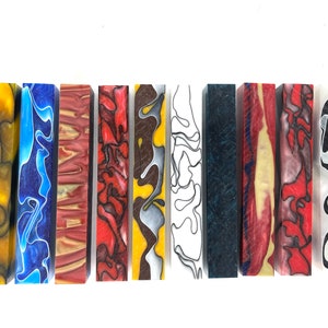May include: Ten different colorful acrylic pen blanks with swirling patterns. The blanks are approximately 6 inches long and 1 inch in diameter.