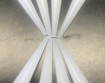 May include: Eight white plastic cones, arranged in a starburst pattern on a dark gray surface.