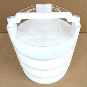 May include: White plastic circular storage rack with four shelves. The rack has a handle on the top and the text "Pen & Mail" and "www.penandmail.com" is printed on the top shelf.