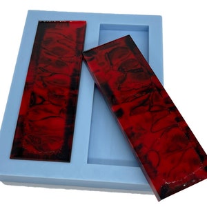 May include: Two red and black resin blanks in a silicone mold. The blanks are rectangular and have a marbled pattern.