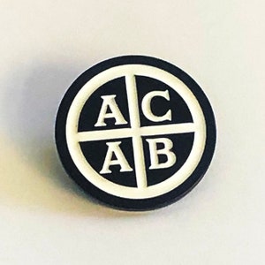 May include: A black and white enamel pin with the letters "ACAB" arranged in a circle.