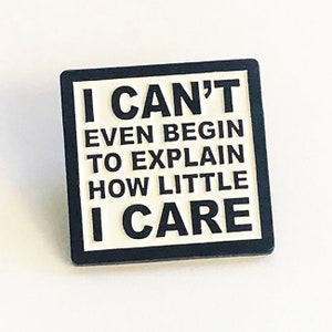 May include: Black and white square pin with the text "I CAN'T EVEN BEGIN TO EXPLAIN HOW LITTLE I CARE" in bold white letters.