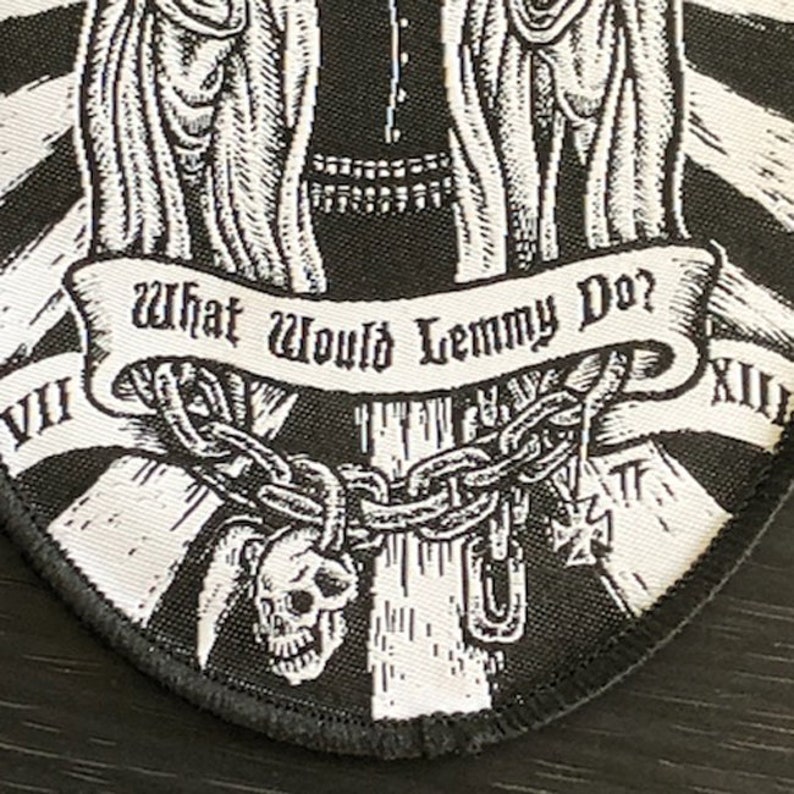 May include: Black and white embroidered patch with a skull and crossbones, a chain, and a banner that reads "What Would Lemmy Do?"