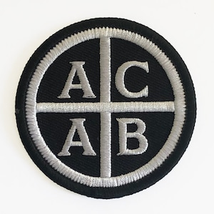 May include: A black and silver embroidered patch with the letters "ACAB" arranged in a cross shape.