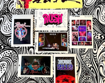Può includere: Una collezione di adesivi e mini-poster della band Rush. Gli adesivi presentano il logo della band, le copertine degli album e le foto dei concerti. La tavolozza dei colori comprende rosso, blu, nero e bianco. Gli articoli sono esposti su uno sfondo a spirale in bianco e nero.