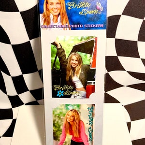 May include: Collectible photo stickers featuring Britney Spears. The packaging is blue and white, with images of Britney Spears in various poses. The text "Britney Spears" and "Collectible Photo Stickers" are visible.