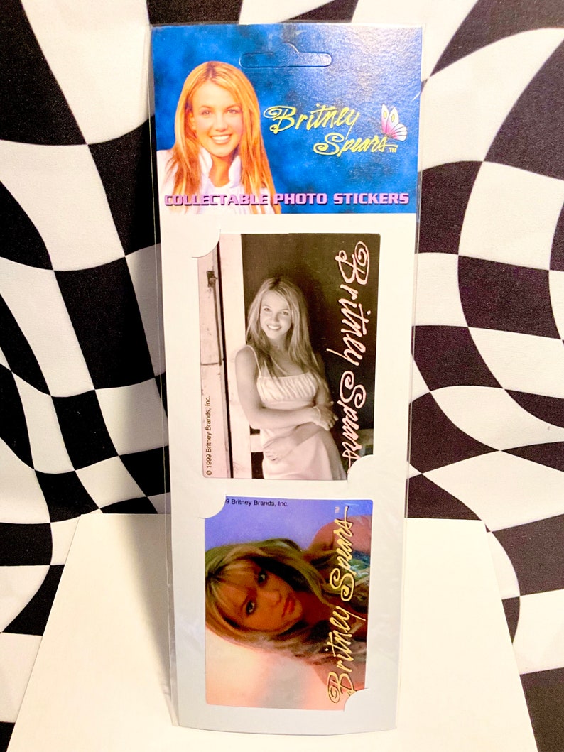 May include: Collectible photo stickers featuring Britney Spears. The stickers have images of Britney Spears in various poses. The top of the package has a blue background with the text "Britney Spears" and "COLLECTABLE PHOTO STICKERS".
