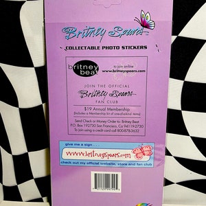 May include: A collectible photo sticker sheet featuring the name "Britney Spears" in a stylized font, with a butterfly graphic. The sheet includes text for a fan club and website address.