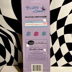 May include: Collectible photo stickers featuring the Britney Spears logo and flower graphics. The packaging includes the text "Britney Spears" and "Collectable Photo Stickers". The stickers are on a purple background.