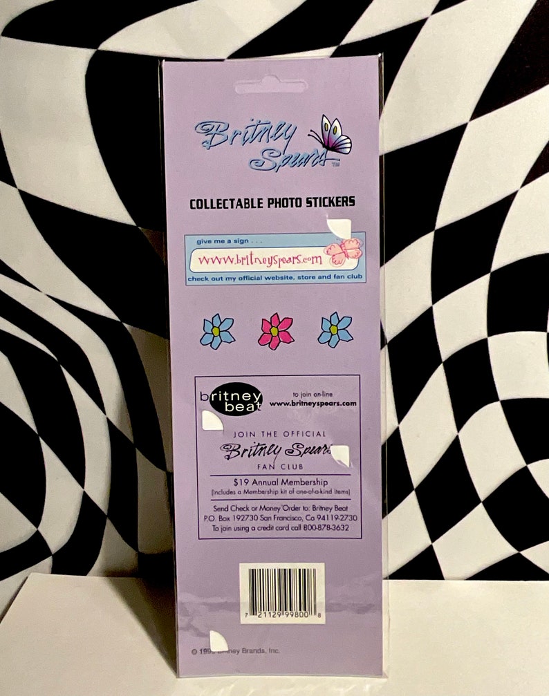 May include: Collectible photo stickers featuring the Britney Spears logo and flower graphics. The packaging includes the text "Britney Spears" and "Collectable Photo Stickers". The stickers are on a purple background.