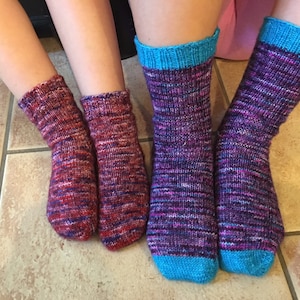 May include: Two pairs of colourful striped socks with blue cuffs. The socks are made of a soft, knitted fabric.