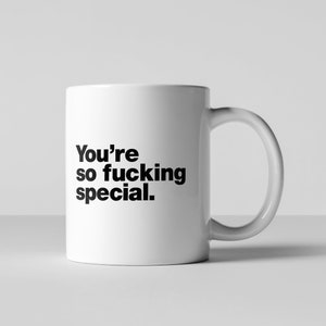 以下が含まれることがあります： 黒い文字で「You're so fucking special.」と書かれた白いセラミック製のコーヒーカップ