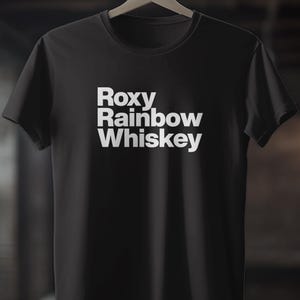 Könnte beinhalten: Schwarzes T-Shirt mit weißem Text, der "Roxy Rainbow Whiskey" lautet