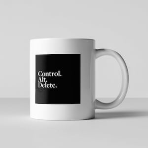 Op de afbeelding: Witte keramische mok met een zwart vierkant ontwerp met de tekst "Control. Alt. Delete."