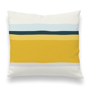 May include: A white throw pillow with a horizontal stripe pattern in shades of yellow, blue, and gray.