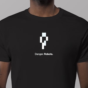 Puede incluir: Camiseta negra con un robot pixelado blanco y el texto "Danger. Robots."
