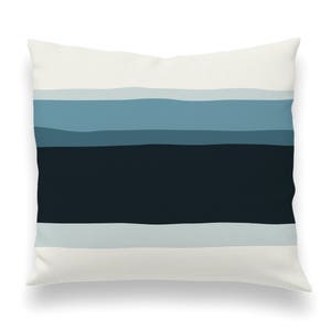 May include: A white throw pillow with a blue and black striped pattern. The stripes are horizontal and fade from light blue to dark blue.