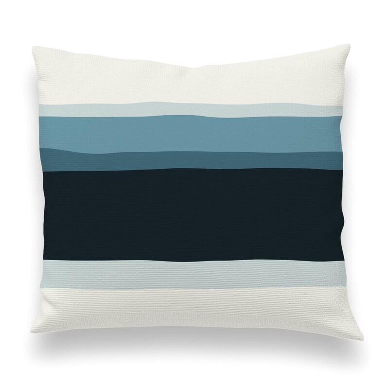 May include: A white throw pillow with a blue and black striped pattern. The stripes are horizontal and fade from light blue to dark blue.