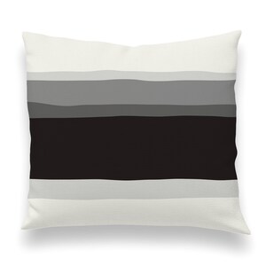 May include: A white pillow with a black and gray striped pattern. The stripes are horizontal and have a slightly wavy texture.