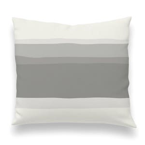 May include: A white throw pillow with a gray ombre stripe pattern. The pillow is soft and comfortable and would be a great addition to any living room or bedroom.
