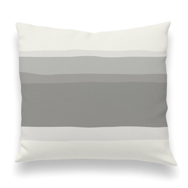 May include: A white throw pillow with a gray ombre stripe pattern. The pillow is soft and comfortable and would be a great addition to any living room or bedroom.