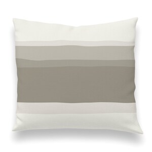 May include: A white throw pillow with a horizontal stripe pattern in shades of beige and brown.