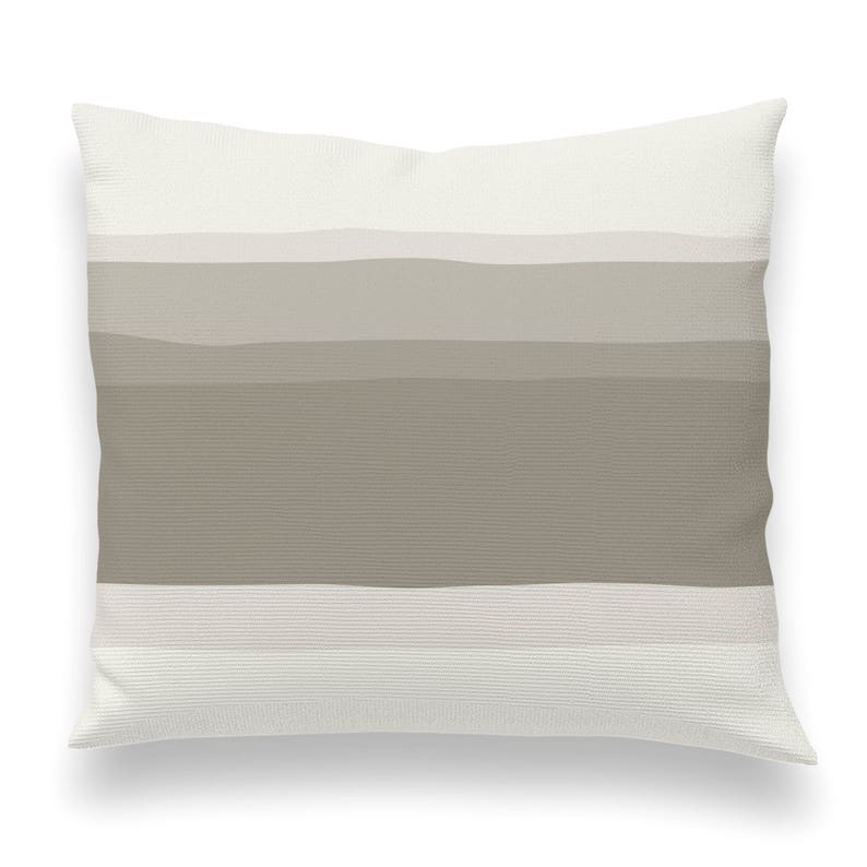 May include: A white throw pillow with a horizontal stripe pattern in shades of beige and brown.