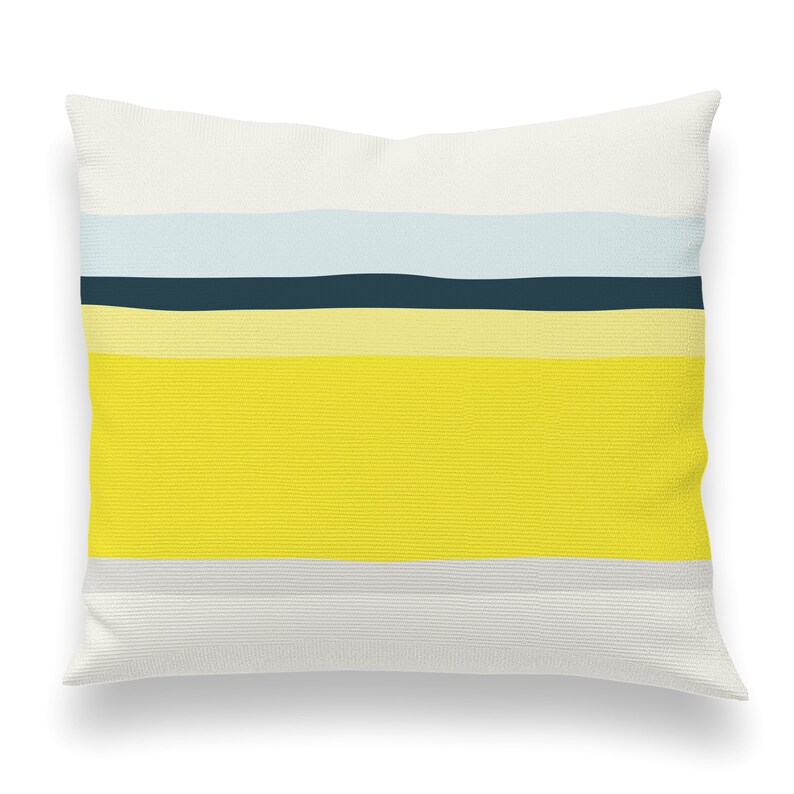 May include: A white pillow with a yellow, light blue, and dark blue striped pattern. The pillow is made of a soft, textured fabric.