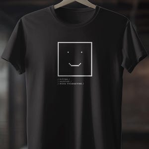 May include: Black t-shirt with a white square containing a pixelated smiley face. Below the square are the words: / FITTER / HAPPIER / MORE PRODUCTIVE /.