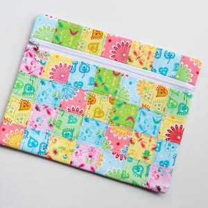 May include: A colorful patchwork zippered pouch with a variety of floral and geometric patterns in shades of pink, blue, green, and yellow.