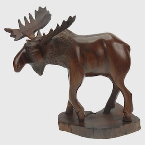 May include: A handcrafted wooden moose sculpture, showcasing a rich brown color and detailed carving. The moose stands on a wooden base, with prominent antlers and a lifelike pose. This decorative piece adds a touch of rustic charm to any space.