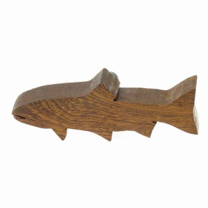 May include: A wooden fish figurine carved in the shape of a trout. The figurine is brown and has a natural wood grain finish.